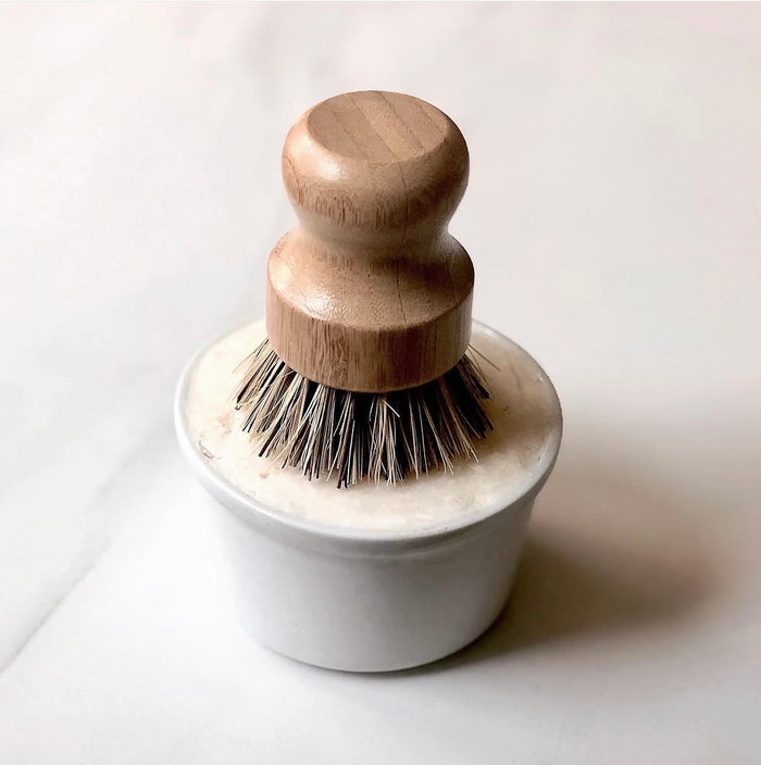Dishwashing brush with wooden handle and white base on a light background