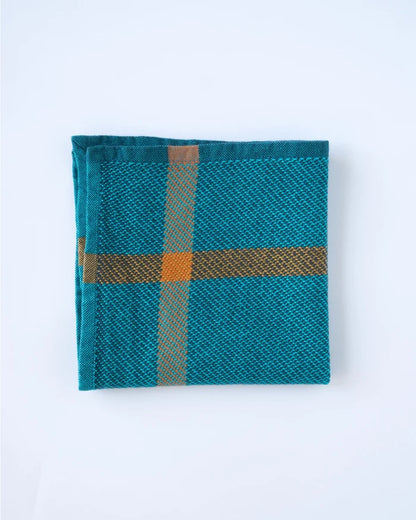 A folded teal woven textile with a plaid pattern in brown and orange, displayed on a clean white background.