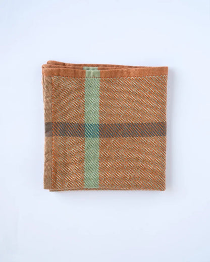 A folded woven textile, likely a pocket square or napkin, featuring a rust-orange base with a vertical sage green stripe and a horizontal dark brown stripe, shown on a plain white background.