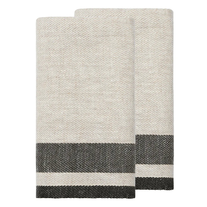 Two folded woven towels in a light oatmeal beige color with a dark charcoal gray and white striped border, displayed on a solid white background.