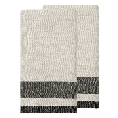 Two folded woven towels in a light oatmeal beige color with a dark charcoal gray and white striped border, displayed on a solid white background.