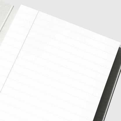 A close-up of a white lined notepad or notebook page with a single vertical ruling, photographed on a light gray background.