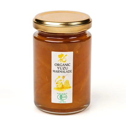 Jar of organic yuzu marmalade with a gold lid on a white background