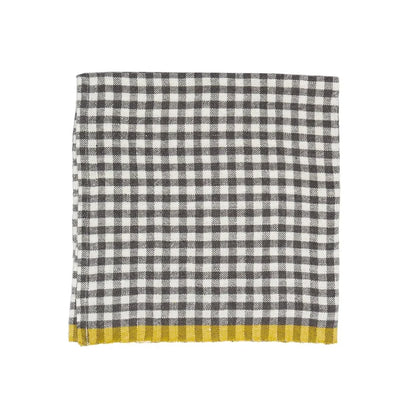 A folded checkered napkin with a black and white gingham pattern and a solid mustard yellow fringed border, shown on a plain white background.