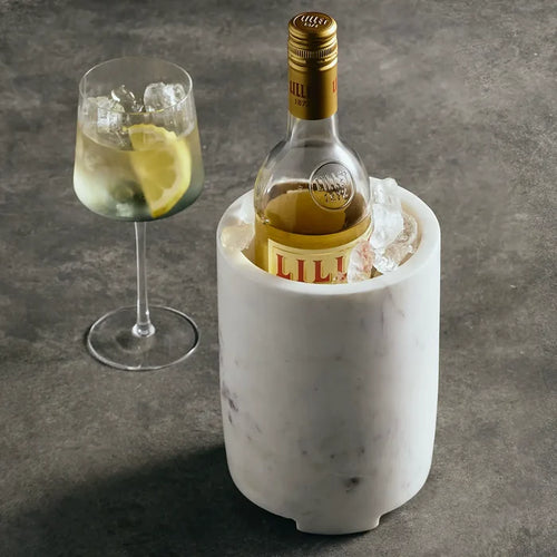 Bottle of Lillet in a marble cooler with a glass of lemonade on a gray surface